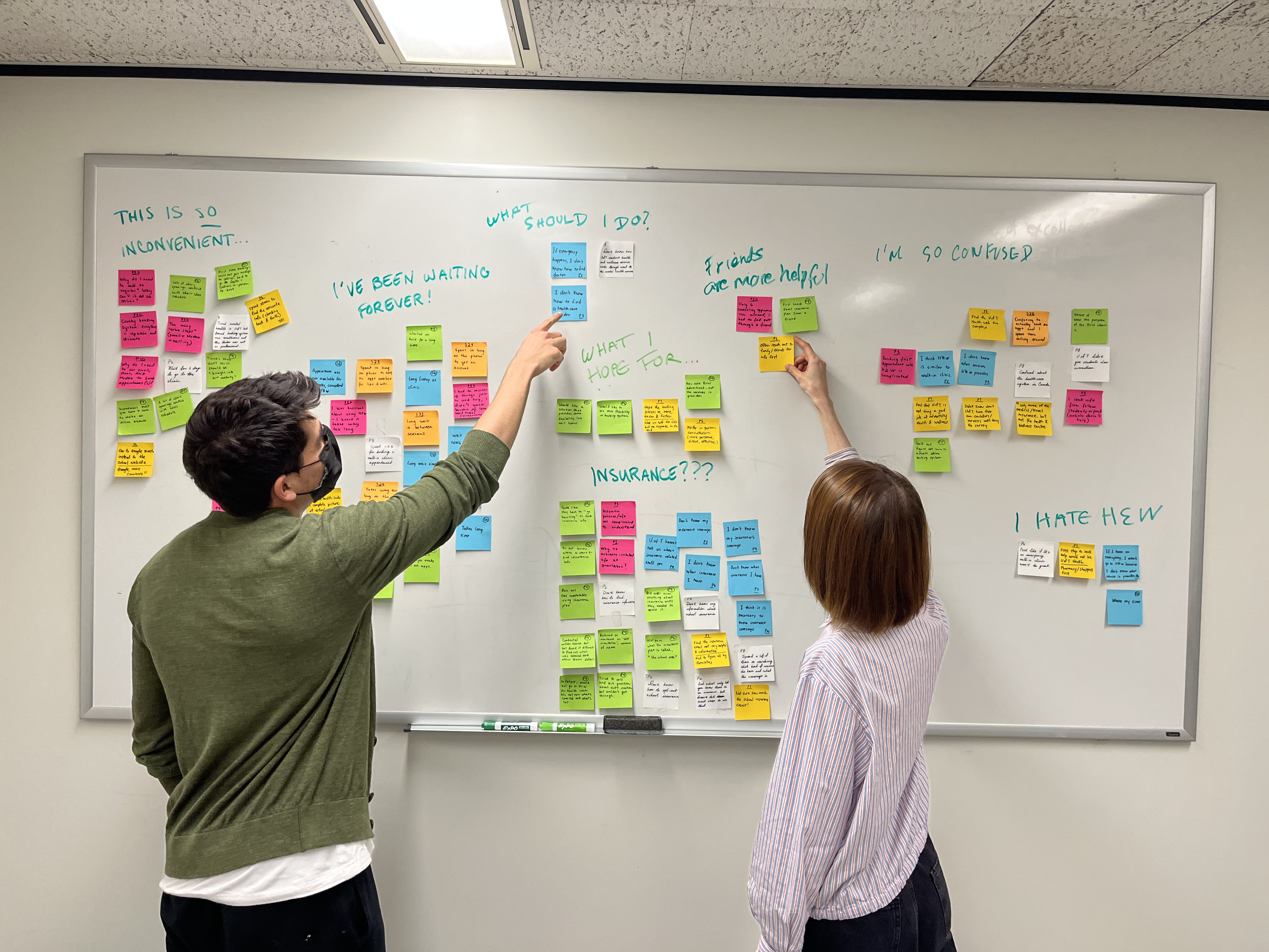 My teammate and me placing sticky notes on a whiteboard as part of affinity diagramming